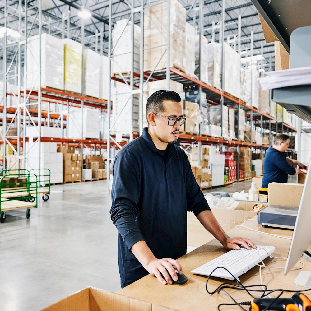 Warehouse worker managing inventory on a computer, showing DP World’s nearshoring and supply chain optimization services.