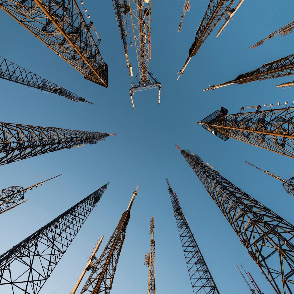 Telecom towers under blue sky, symbolizing DP World’s real-time supply chain sync via North American time zone alignment.